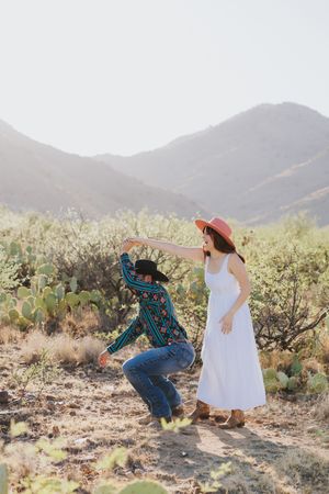 Playful dance sequence captured in desert setting with mountain backdrop.