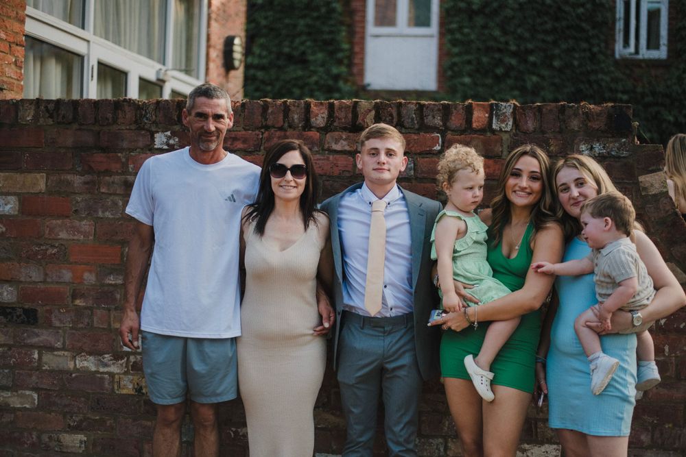 Group photo of guests at a formal gathering posing against a brick wall background.