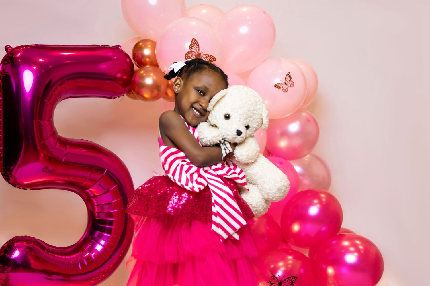Birthday celebration setup with pink balloons and a large magenta number 5.