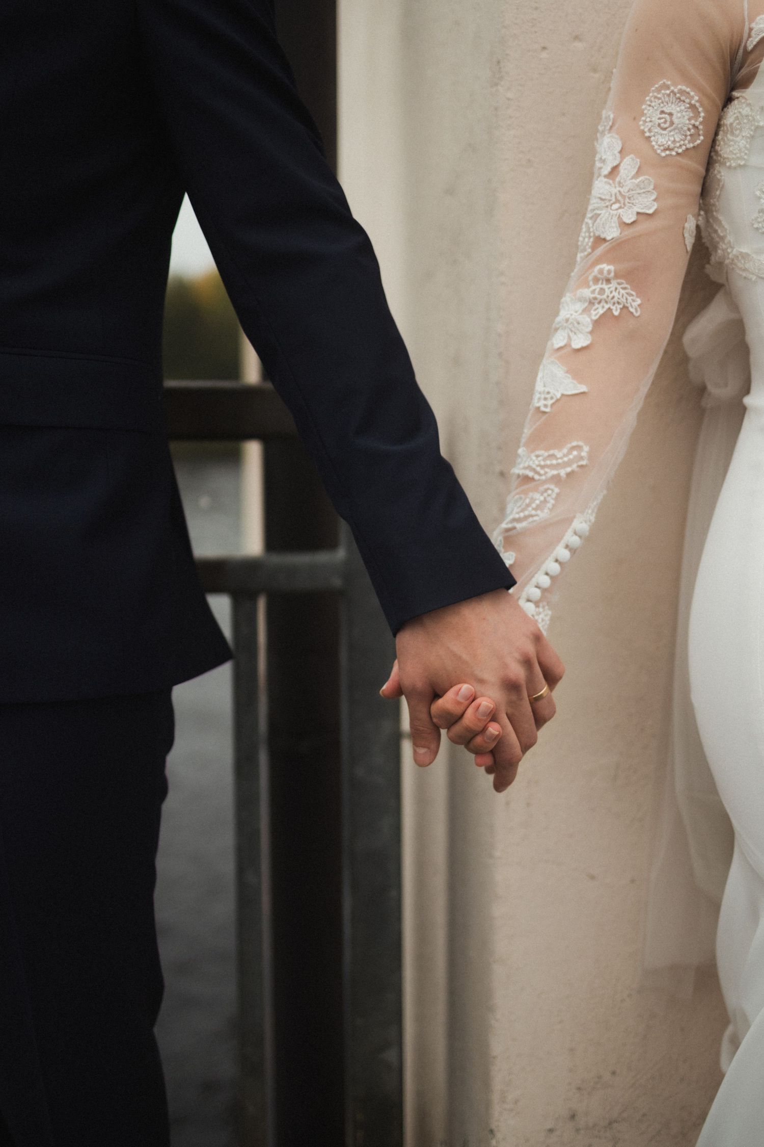 Close-up of couple holding hands showing lace sleeve detail.