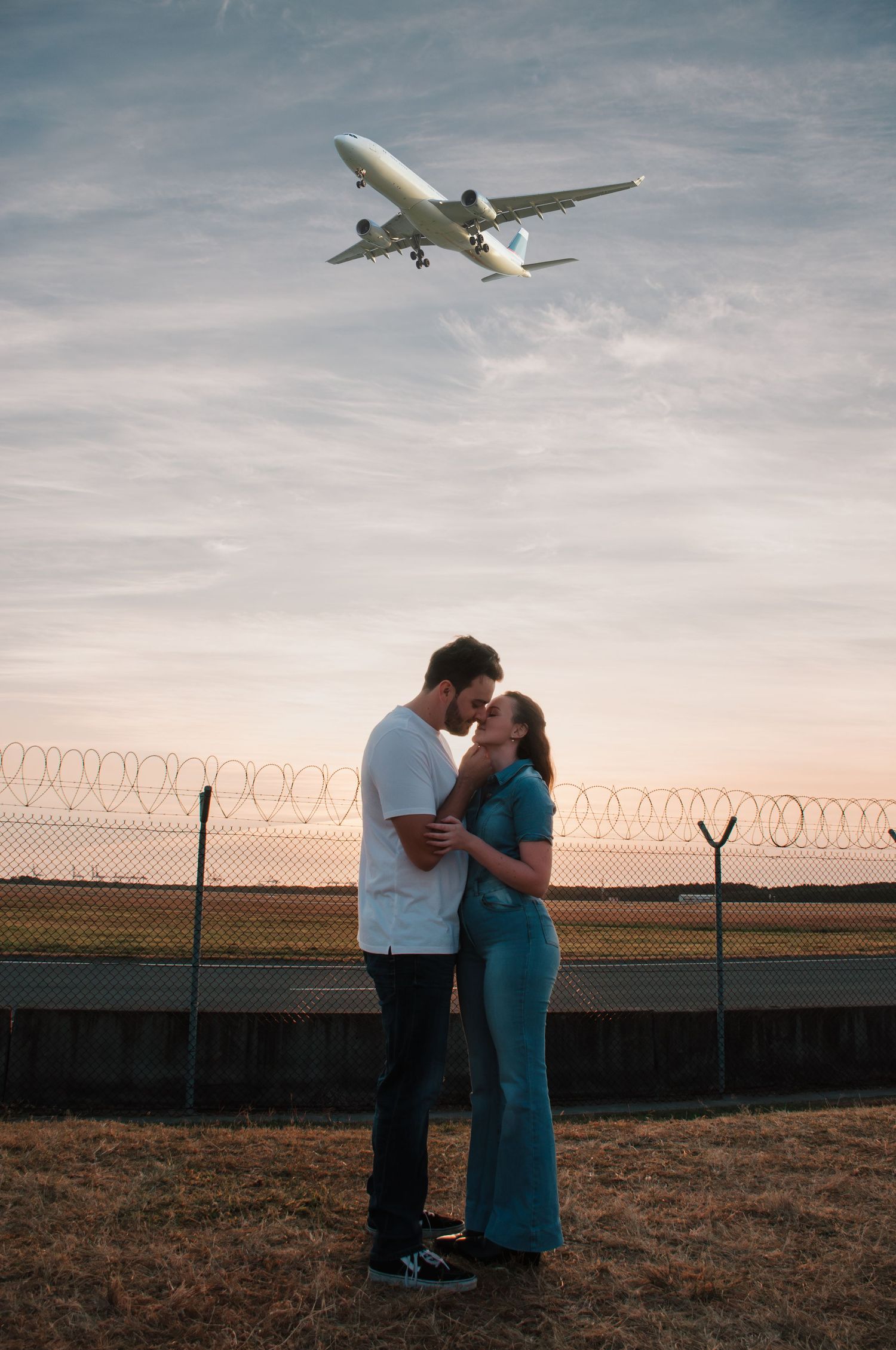couple kissing under a plane. A plane flies over the couple as they connect during a couples photoshoot