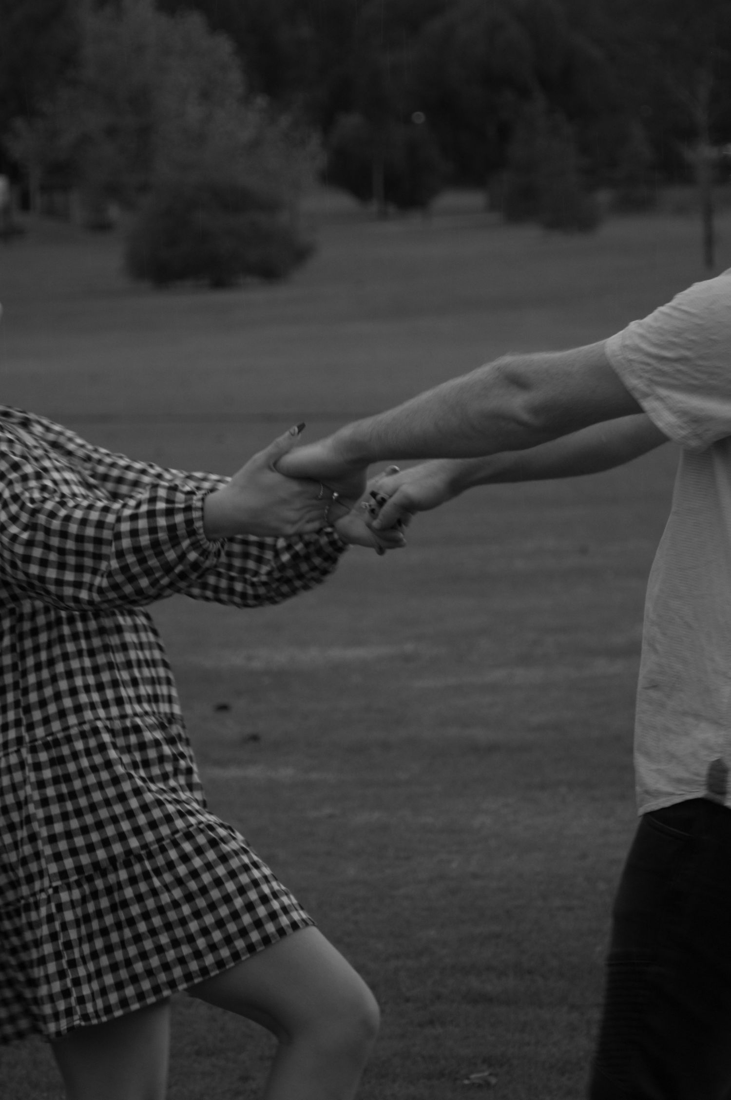couple playing in the rain. close up of the couple holding hands as they spin each other around in the rain