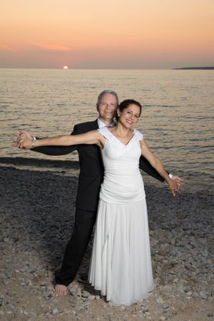 A beachside sunset wedding couple posing with arms outstretched on Lake Michigan in Petosky, MI