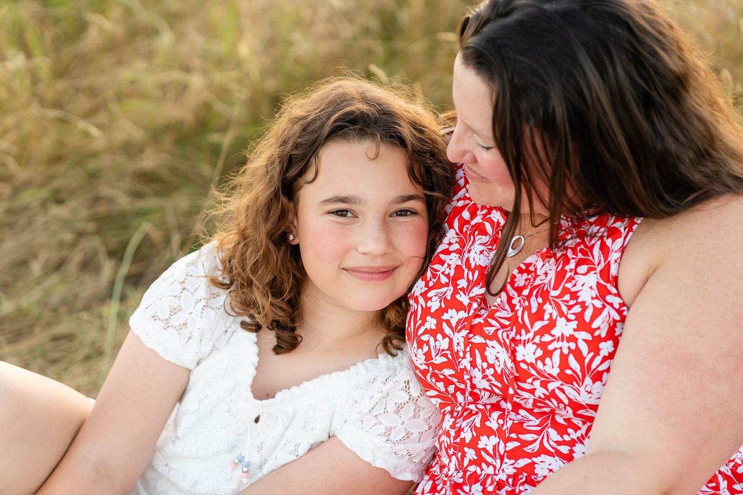 Mother and daughter cuddle together while seated on a blanket in Redmond.