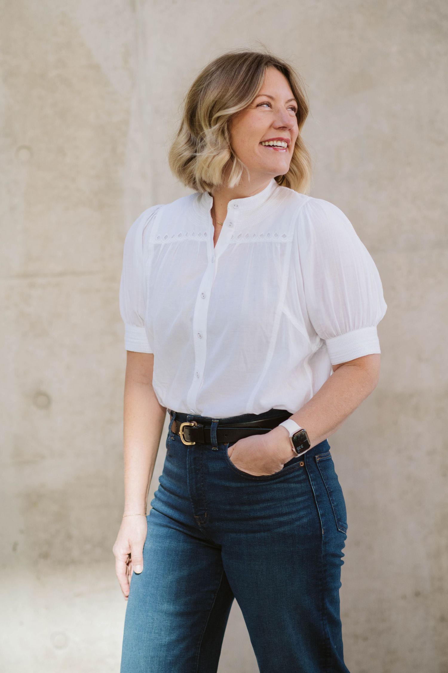 Classic outfit styling featuring white blouse and dark denim jeans with belt.