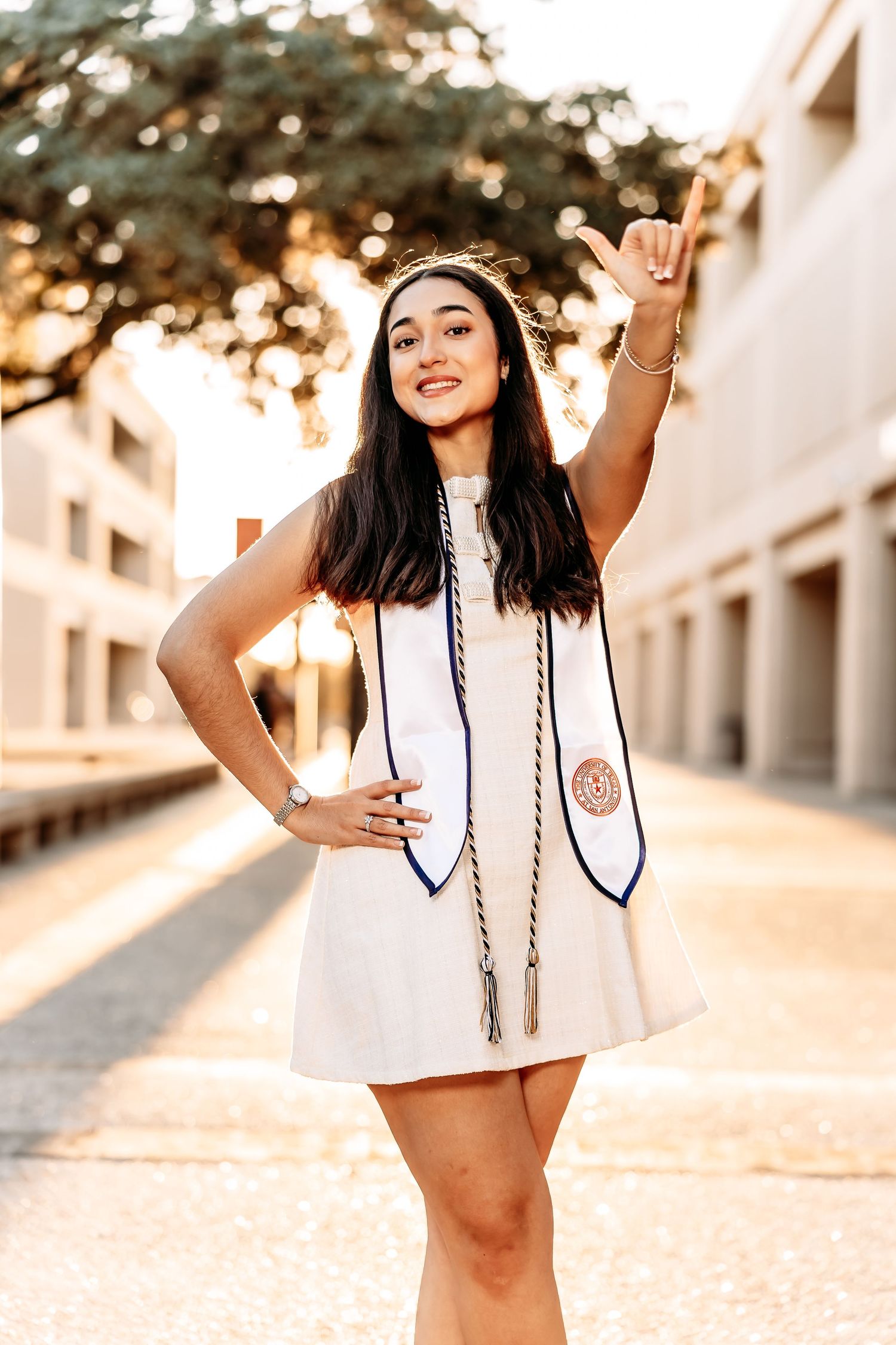 A series of five connected photos showing a cheerleader in a white uniform posing outdoors at sunset.