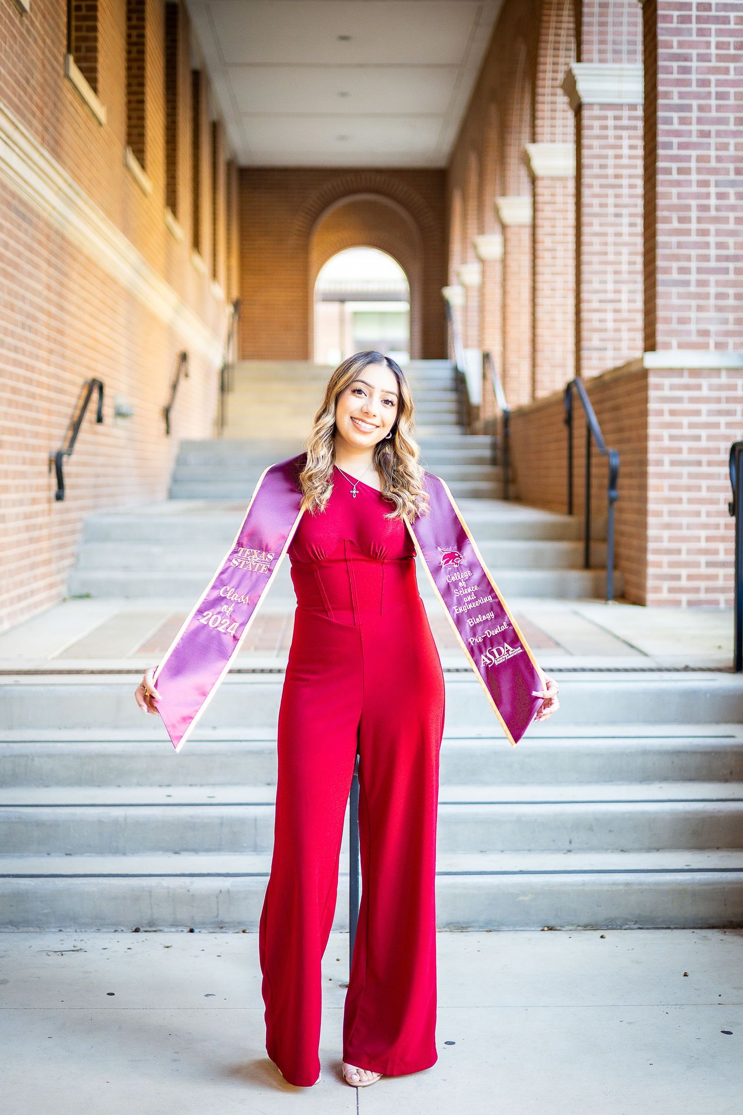 A series of graduation photos showing a red cap and gown in a brick hallway with arched windows.