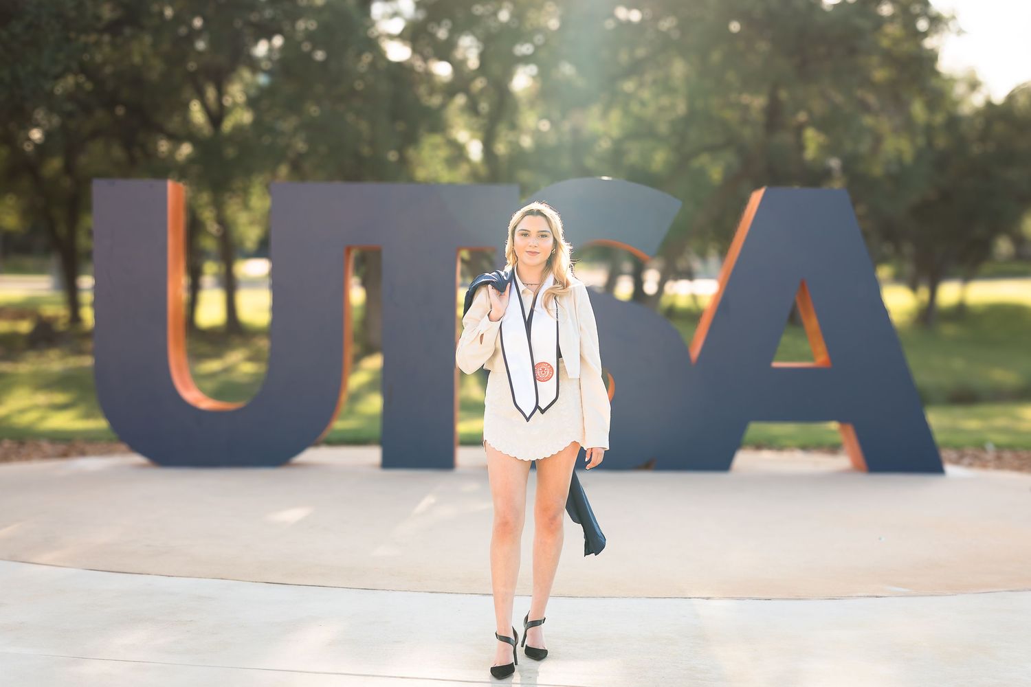 A person in a white dress poses playfully in front of large colorful outdoor letters spelling UTAH.