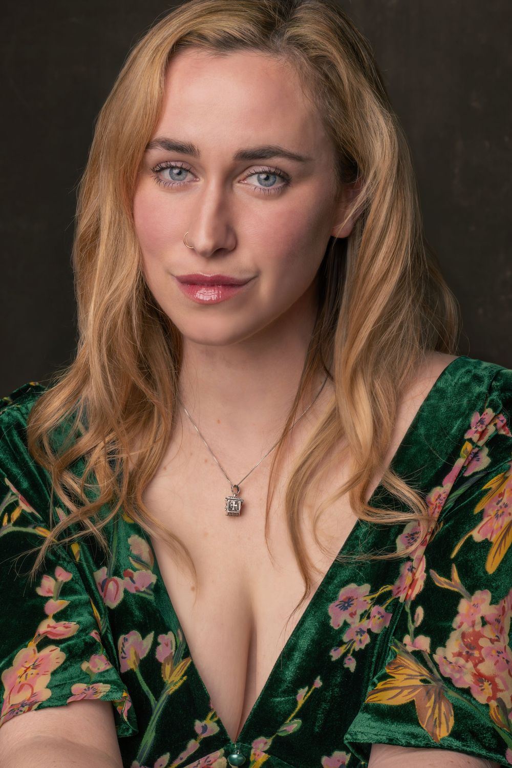 A portrait of someone wearing a green floral velvet dress against a dark background.