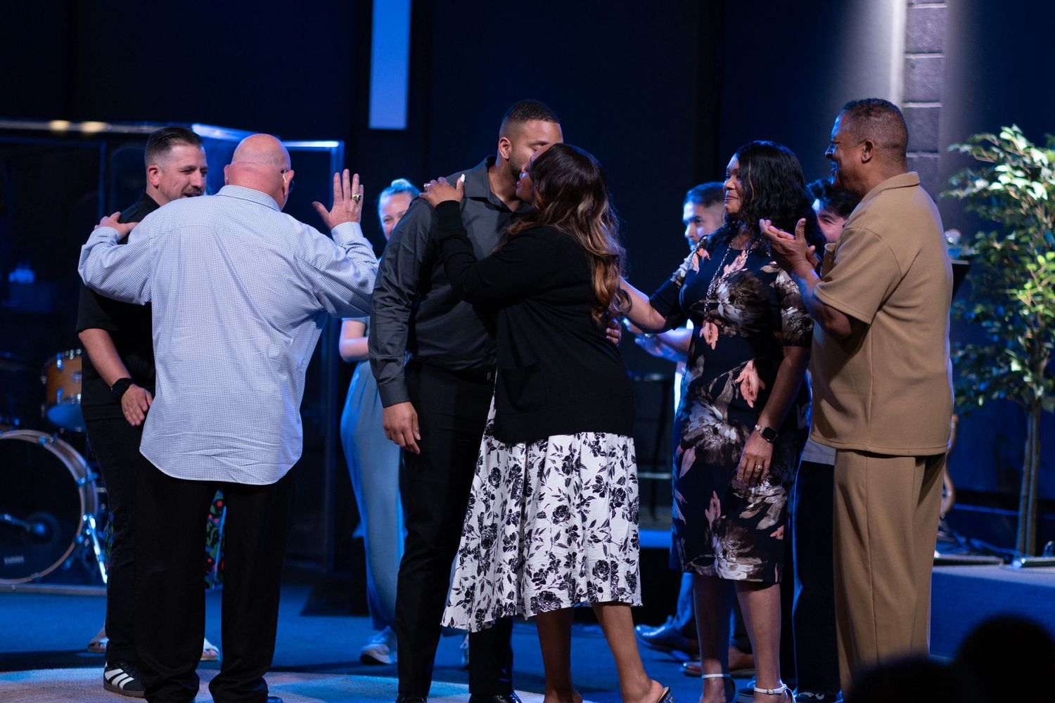 Group of people praying together on a church stage during a worship service.