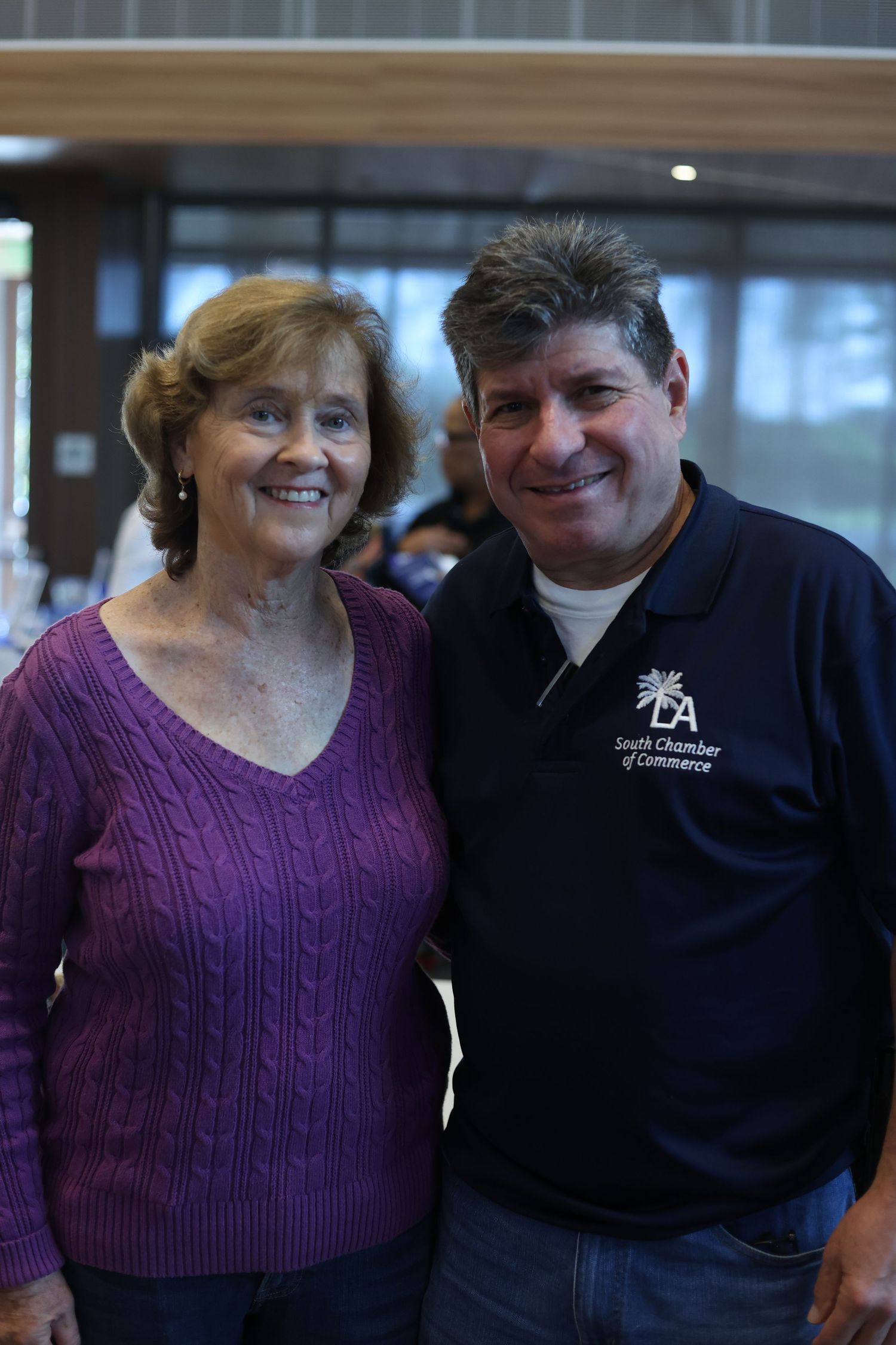 Two smiling adults pose together, man wearing South Chamber of Commerce navy polo shirt, woman in purple sweater.