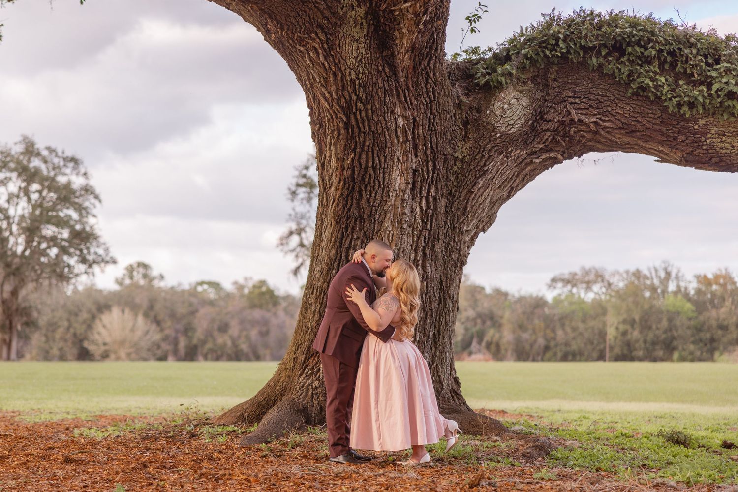 A couple embraces beneath a large oak tree during a Central Florida portrait session.
