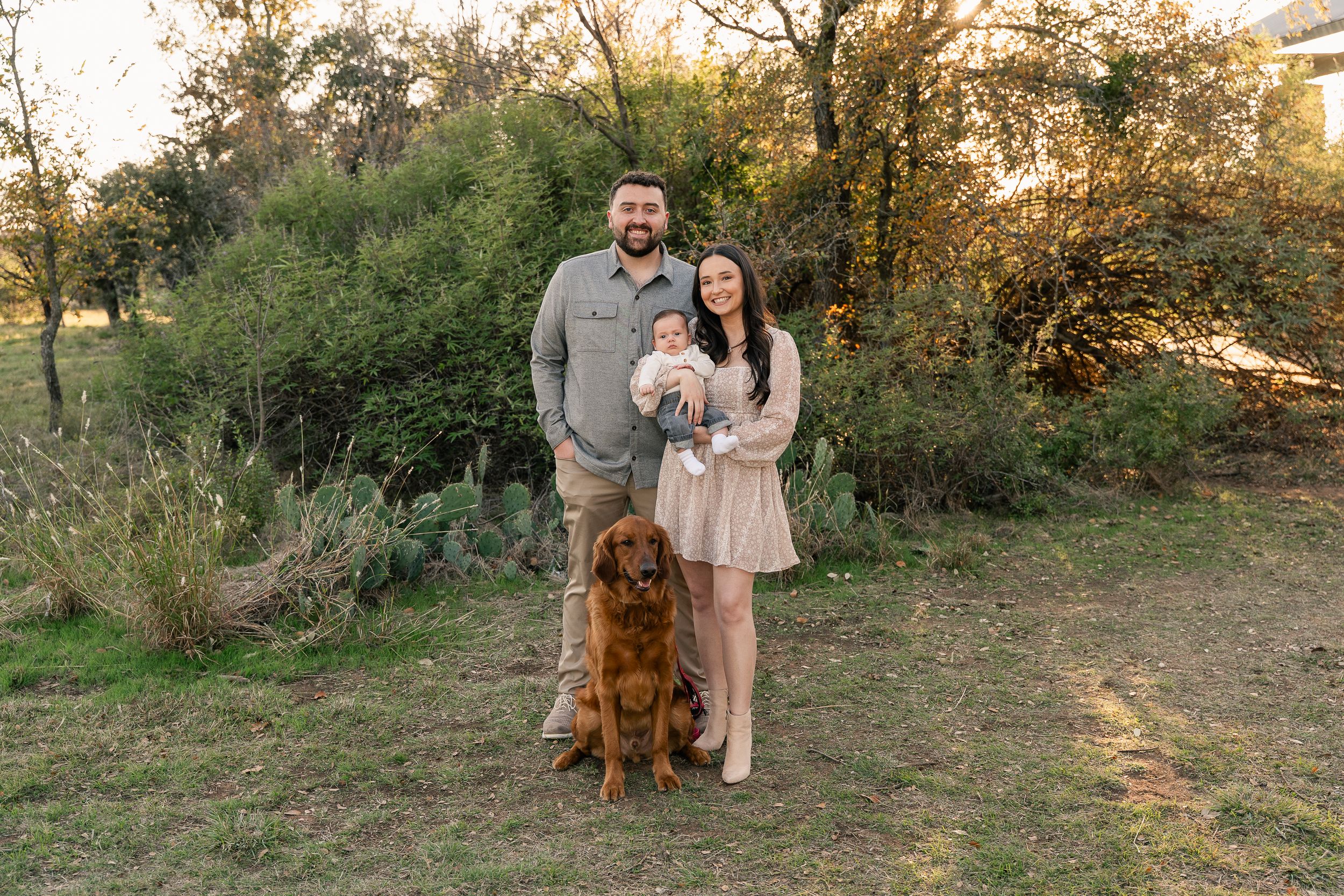 Family Photoshoot at Eagle Mountain Park. Parents hold their newborn and smile at the camera with their golden retriever.