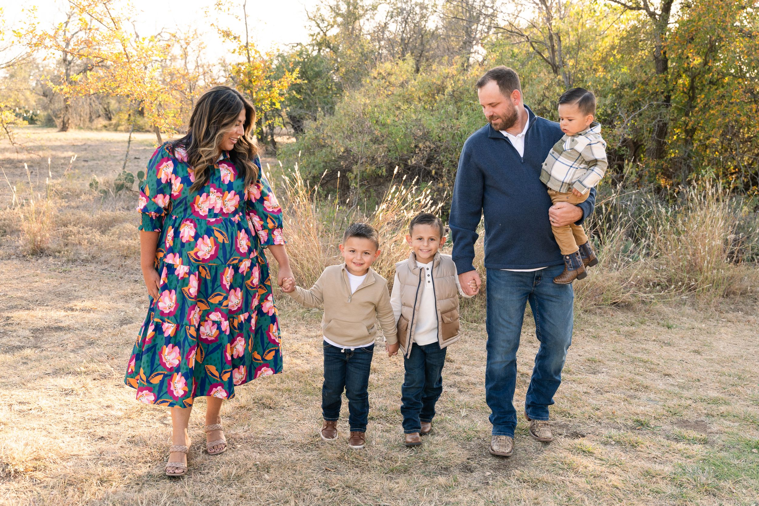 Fall Mini Session in Eagle Mountain Park, TX. Everyone holds hands and walks while mom and dad smile at each other.