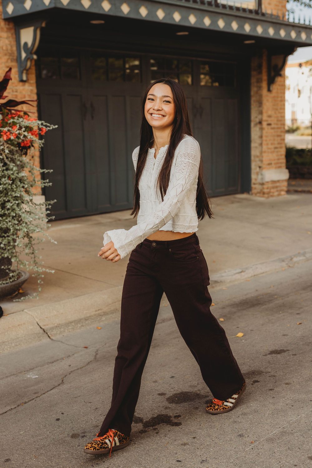 Fashion portrait showing casual outfit with wide-leg pants and white top against brick building.
