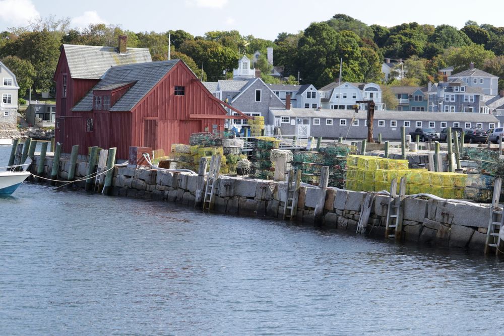 Row of colorful boathouses and docks along a waterfront marina with red buildings.