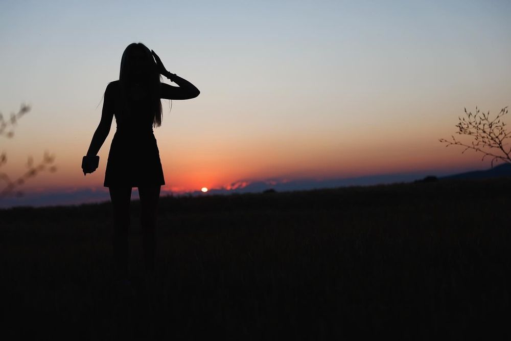 Silhouettes of figures walking along a nature trail against a dramatic sunset sky.
