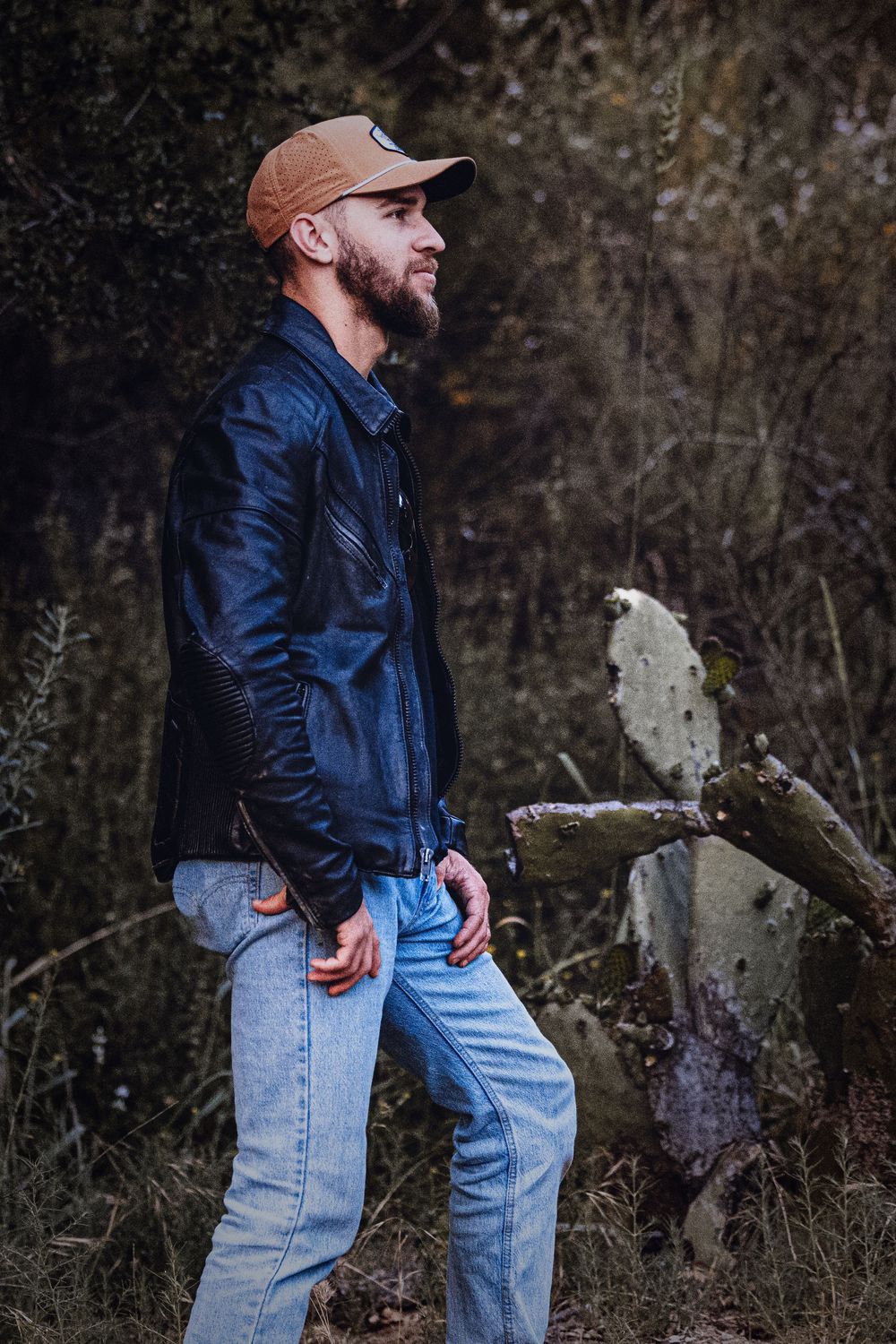 Casual outdoor portrait session featuring denim and leather fashion against natural backdrop.
