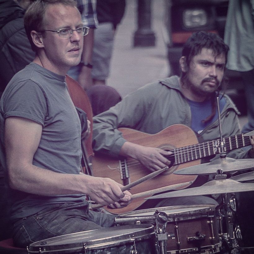 Band members performing on stage with guitars and drums during a live show.