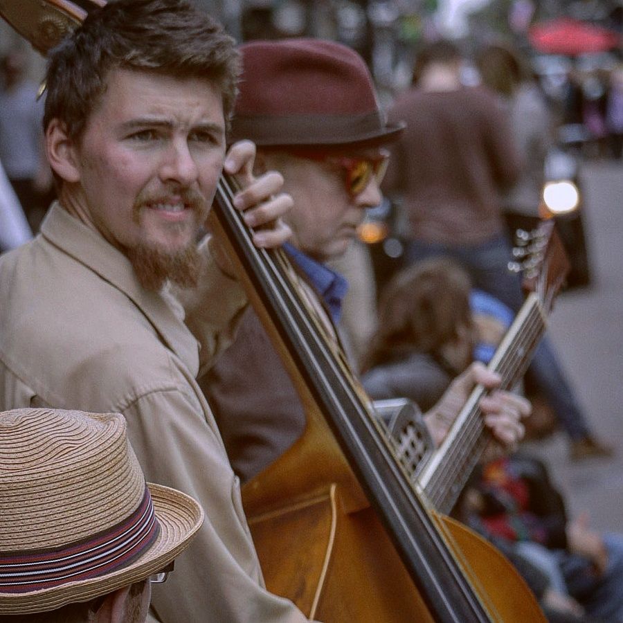 Musicians performing with string instruments while wearing vintage-style straw hats.