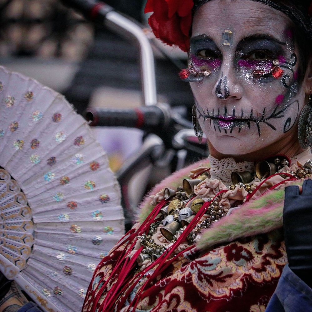 Performers wearing elaborate face paint and traditional fans in a cultural celebration.
