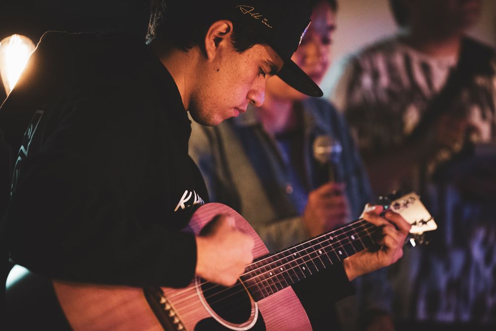 Musicians performing on stage with guitars under atmospheric lighting.