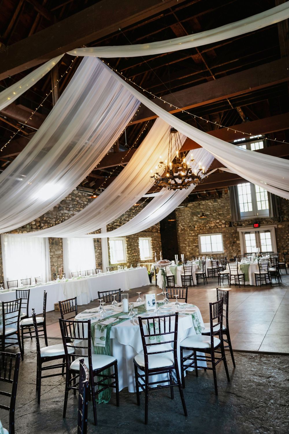 Knights Castle wedding venue with white fabric draping and elegant table settings featuring stone walls and natural lighting.