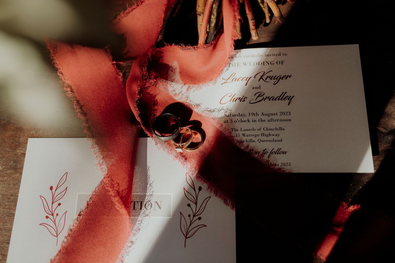 Wedding invitation details with elegant red ribbons and floral design elements in dramatic lighting.