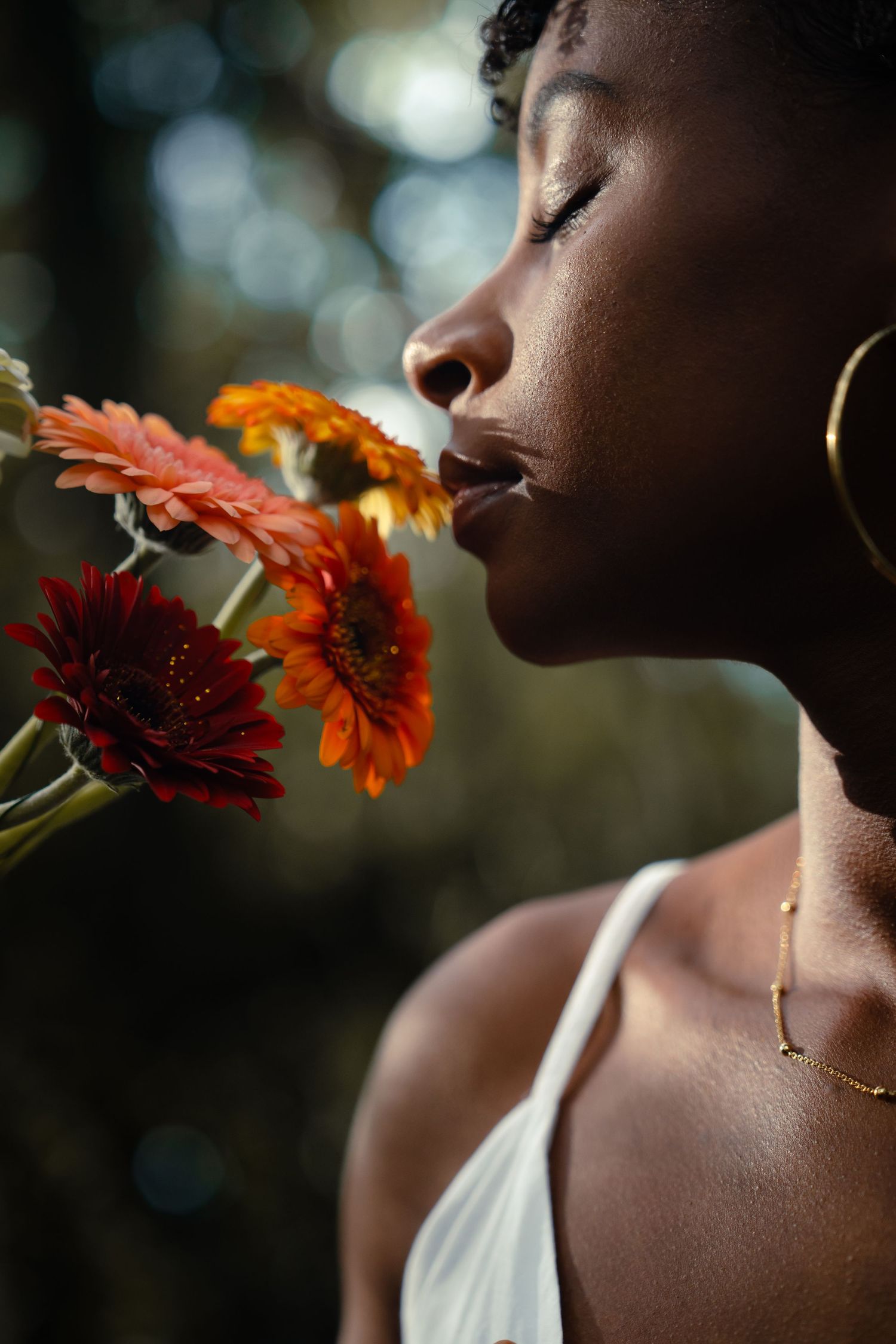 Portrait de profil d'une femme sentant des fleurs, lumière naturelle