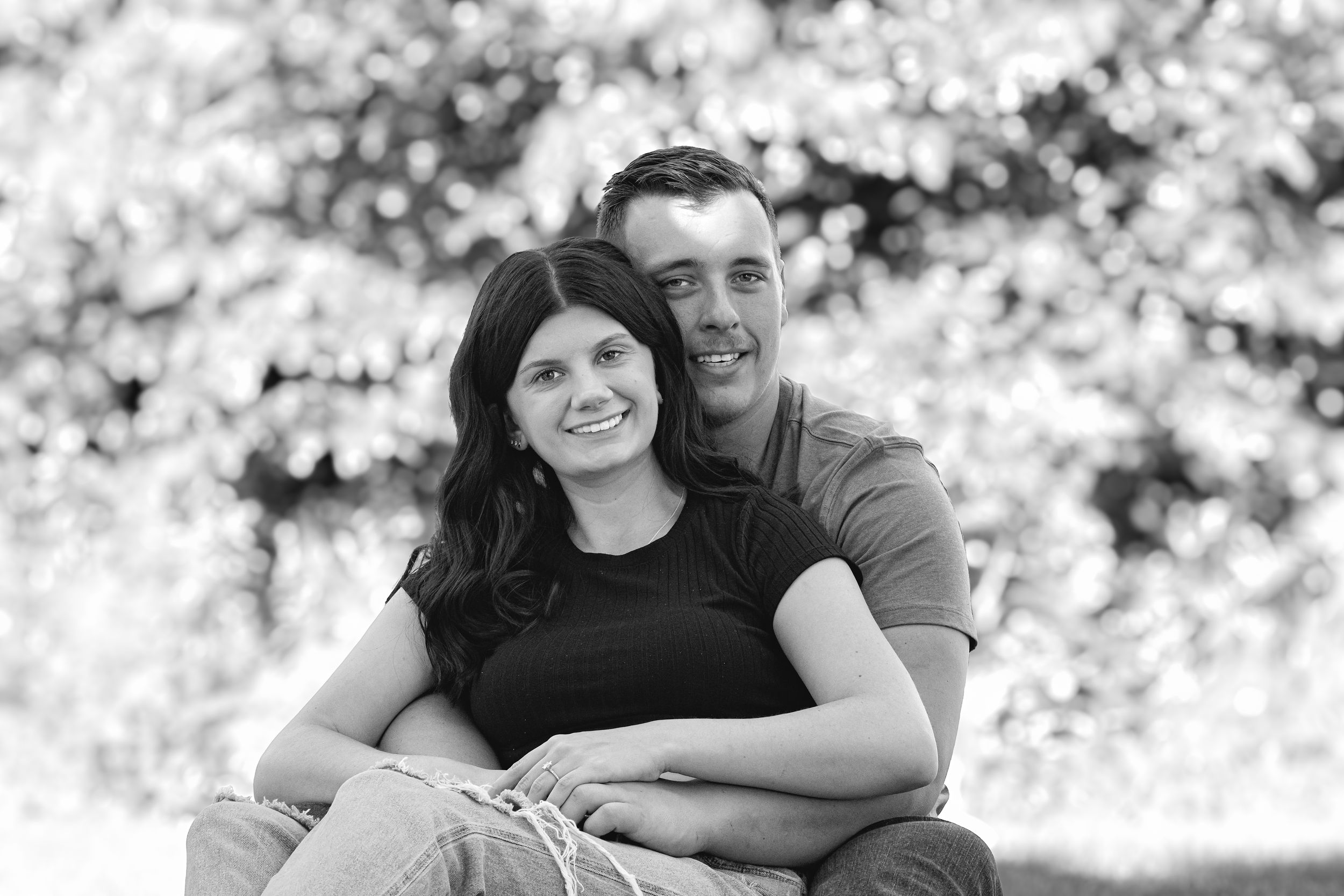 Loving couple poses for casual engagement photos in dappled sunlight.