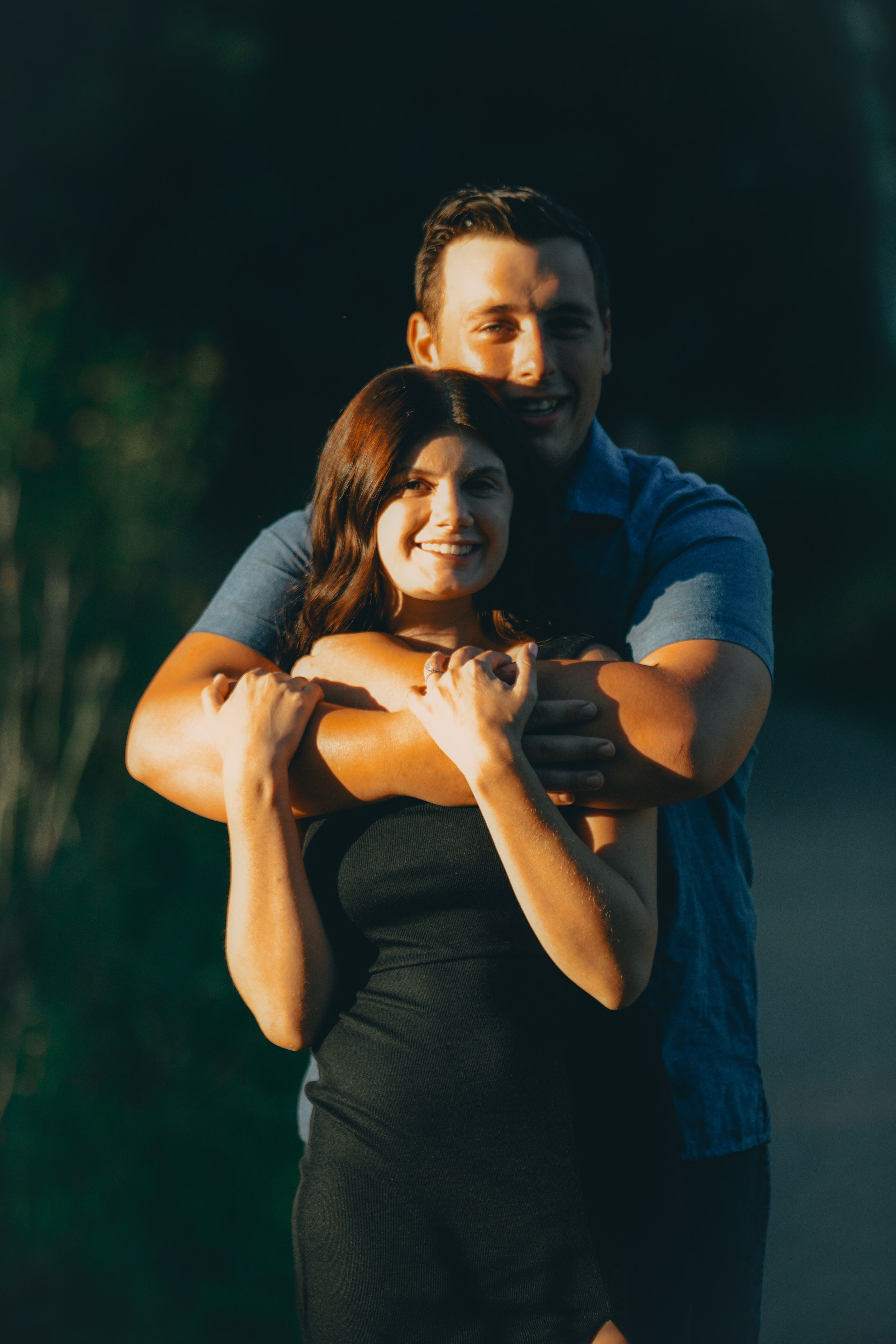 A couple dancing outdoors at sunset shares an intimate moment in a romantic embrace.