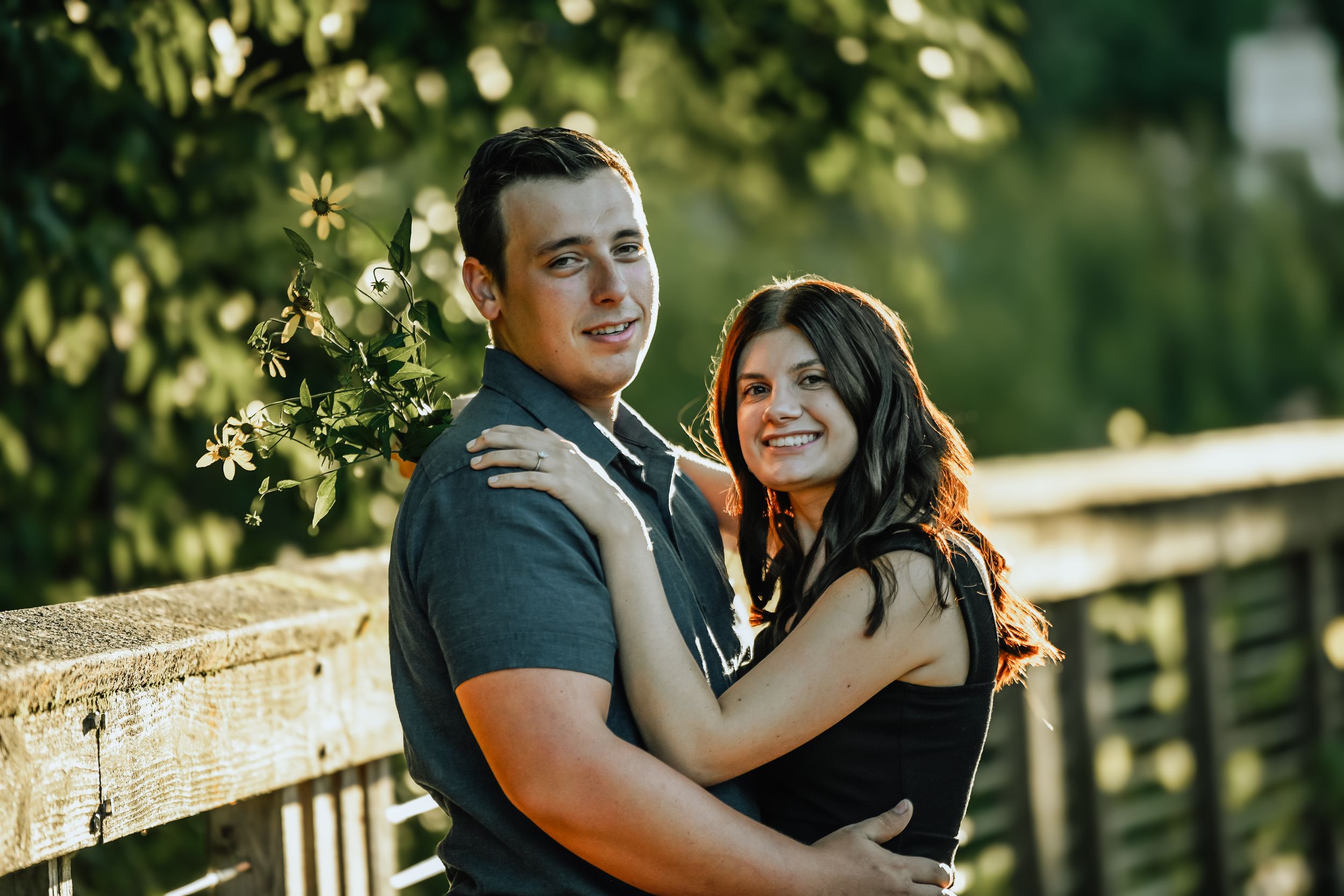 Two people pose together on a bridge railing during a romantic sunset session.