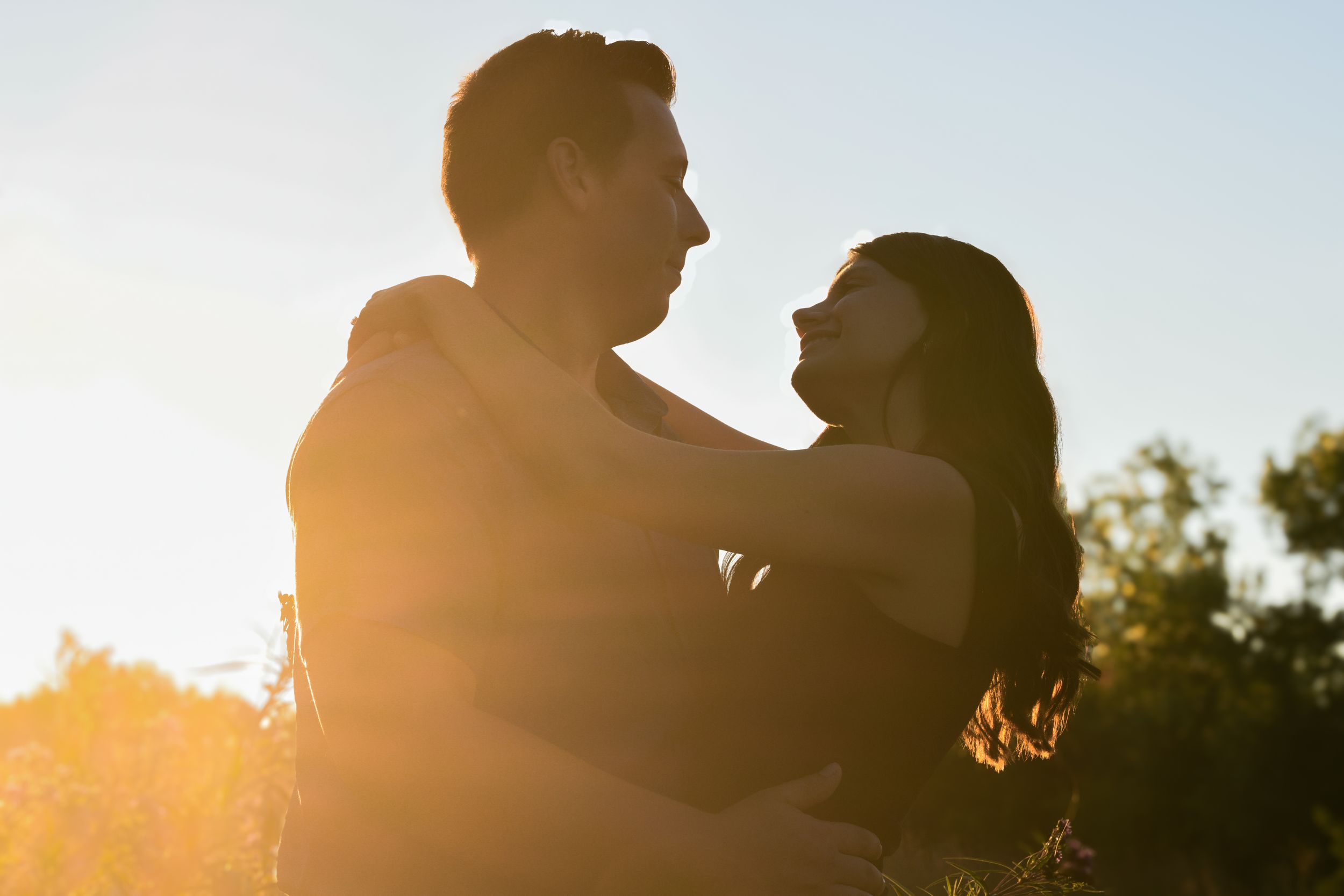 Romantic silhouettes against a bright sunset sky create an intimate moment.