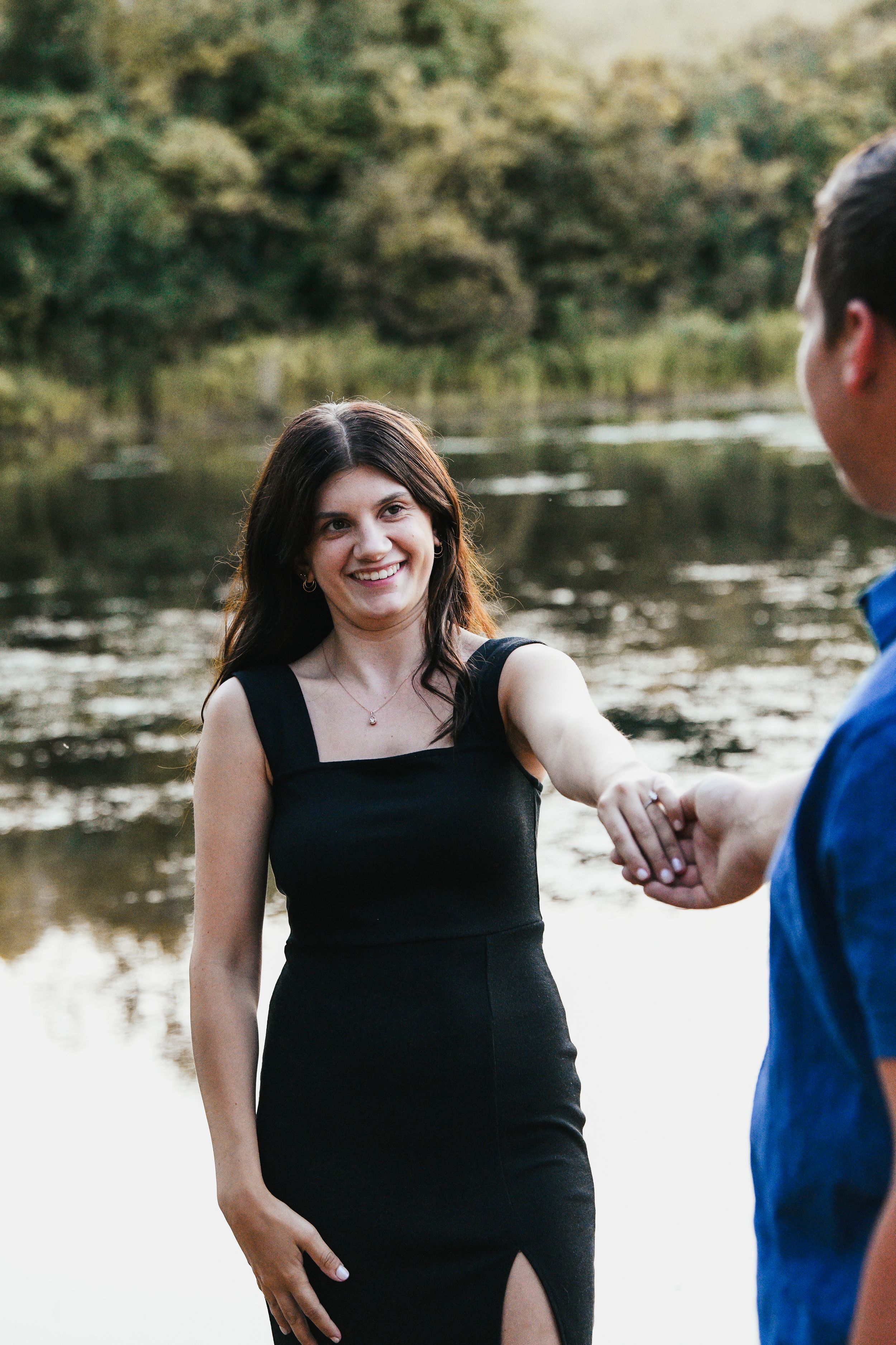 Couple posing playfully by a lake during an outdoor photoshoot.