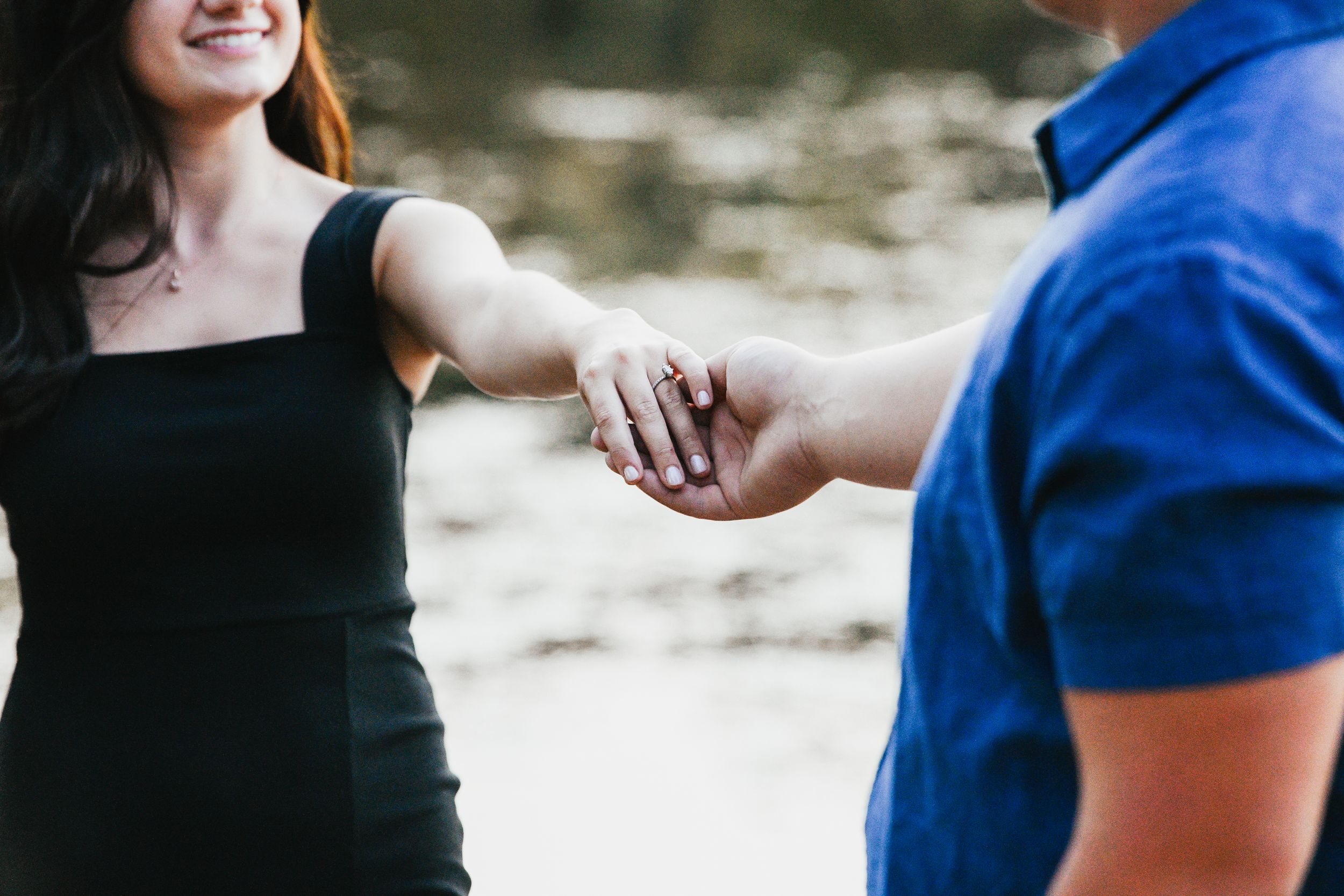Joyful couple holding hands and sharing laughter by the water.
