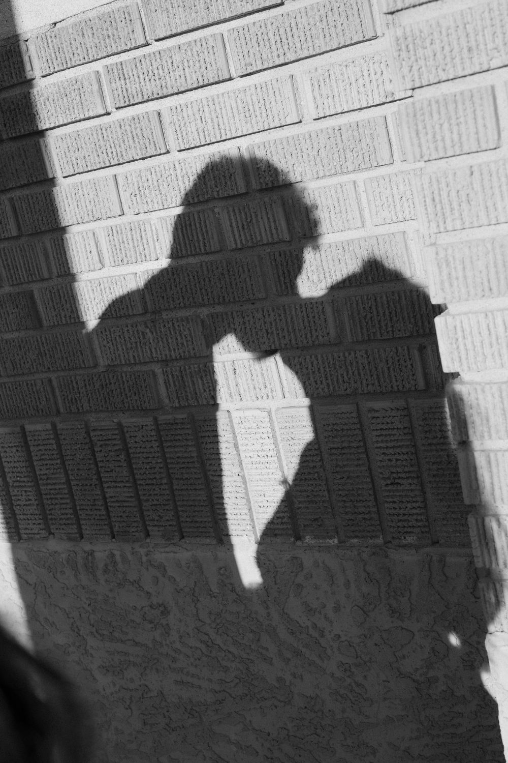 Shadow silhouette of a romantic couple against a white brick wall.