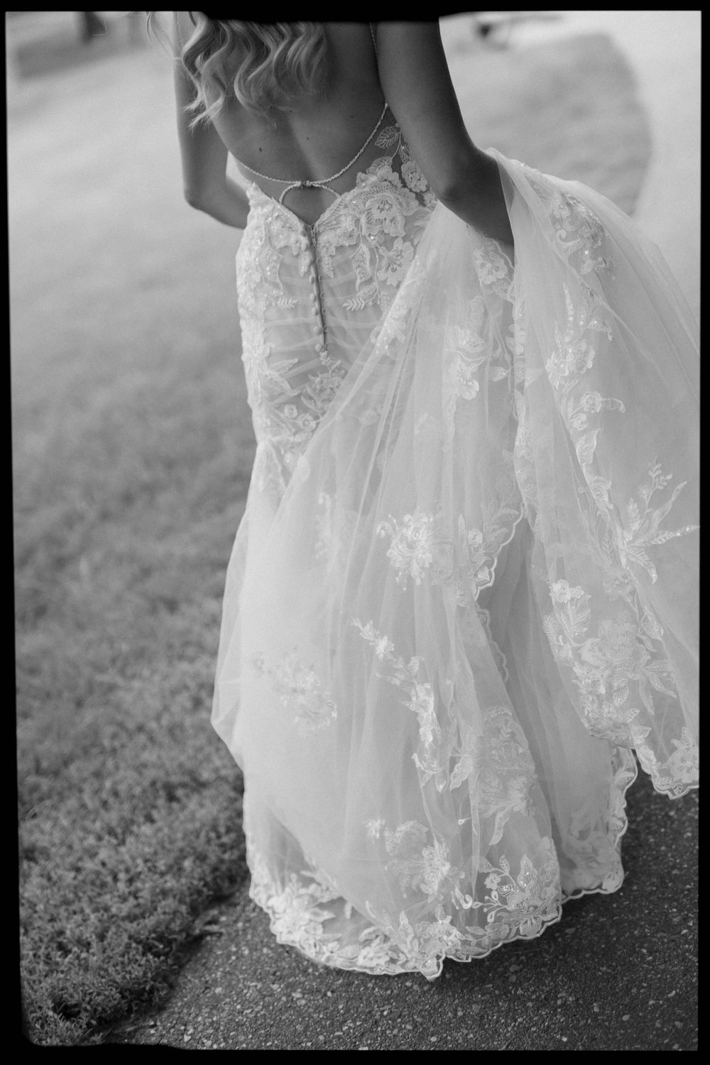 Detail shot of intricate lace wedding dress hem against the ground.