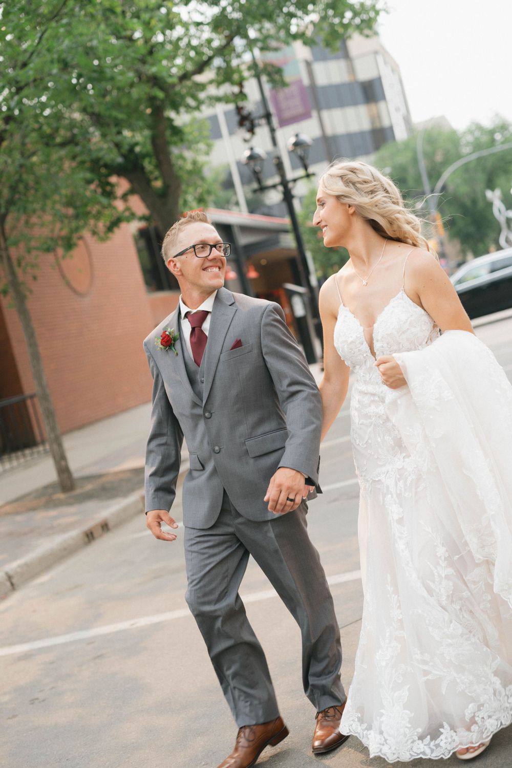 Candid moment of newlyweds walking and laughing together on a city street.