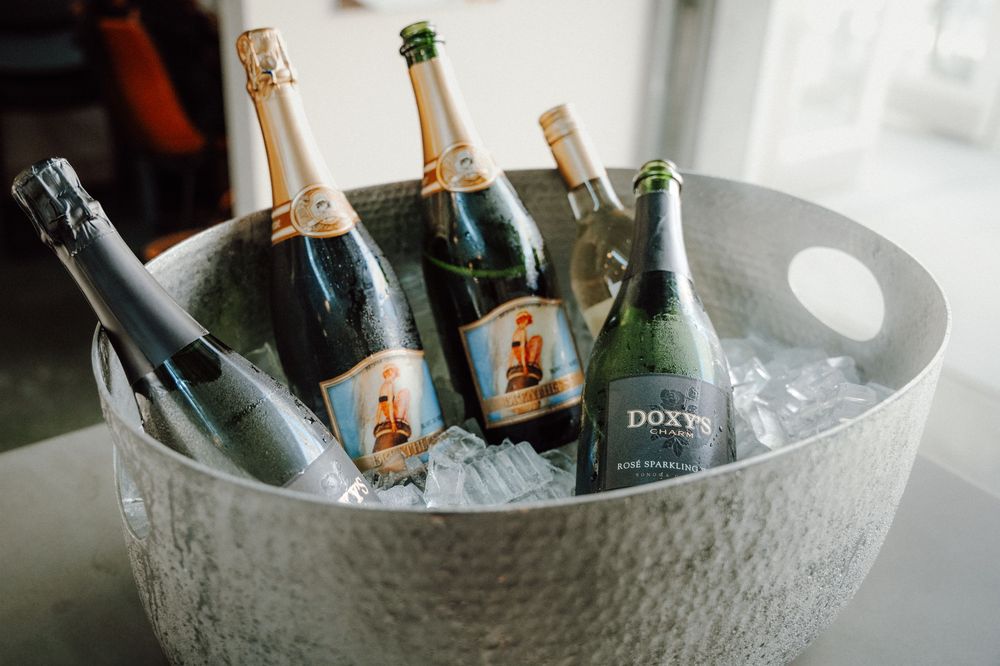 Chilled champagne bottles nestled in ice inside a large hammered metal serving bowl.