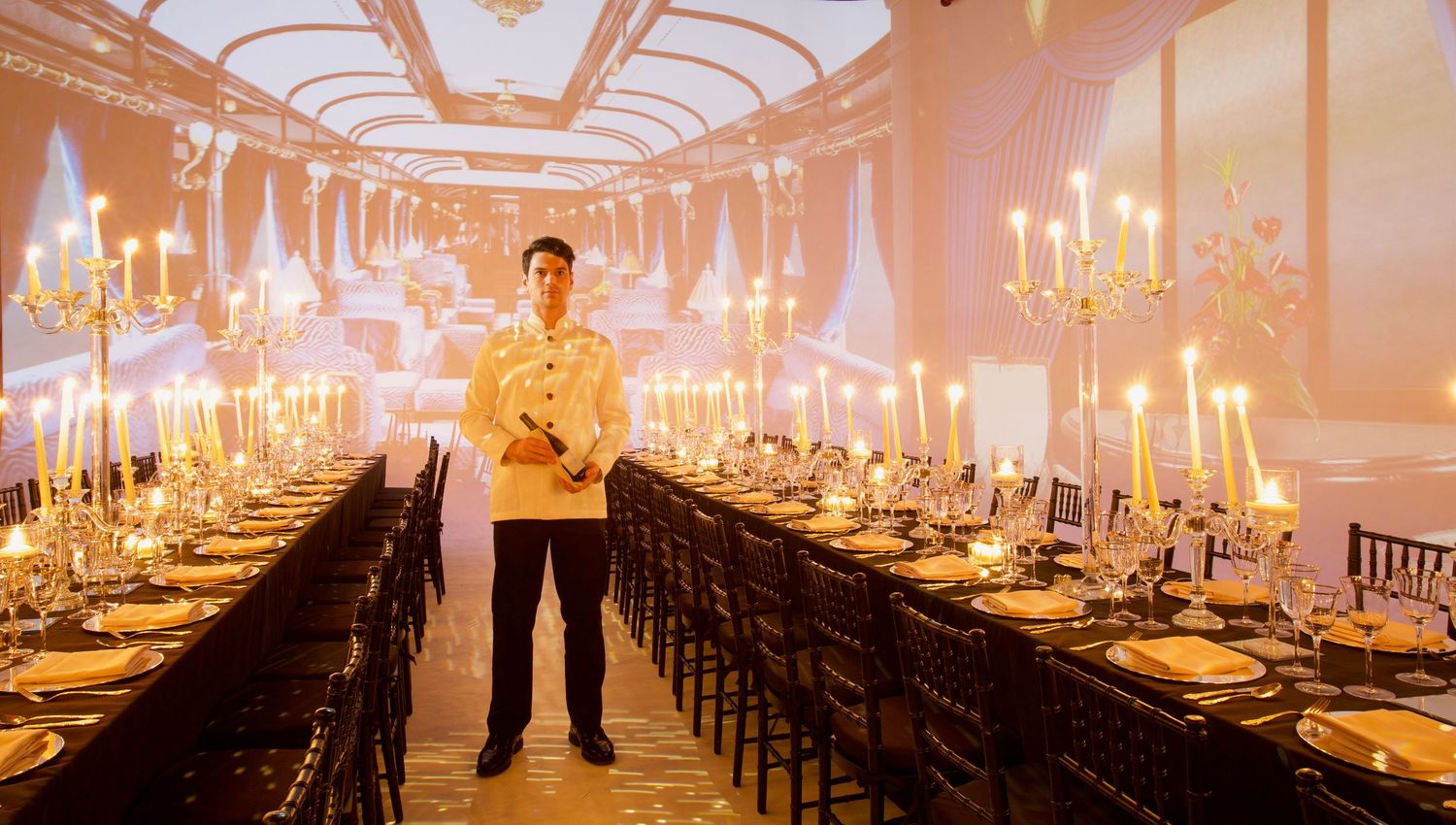 A luxury banquet hall with long tables set with golden candelabras and fine dinnerware illuminated by warm candlelight.