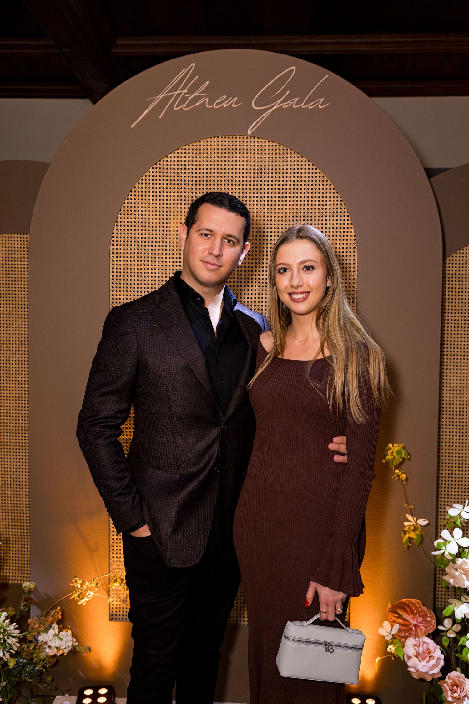 People at an elegantly decorated event space with floral arrangements and warm ambient lighting.
