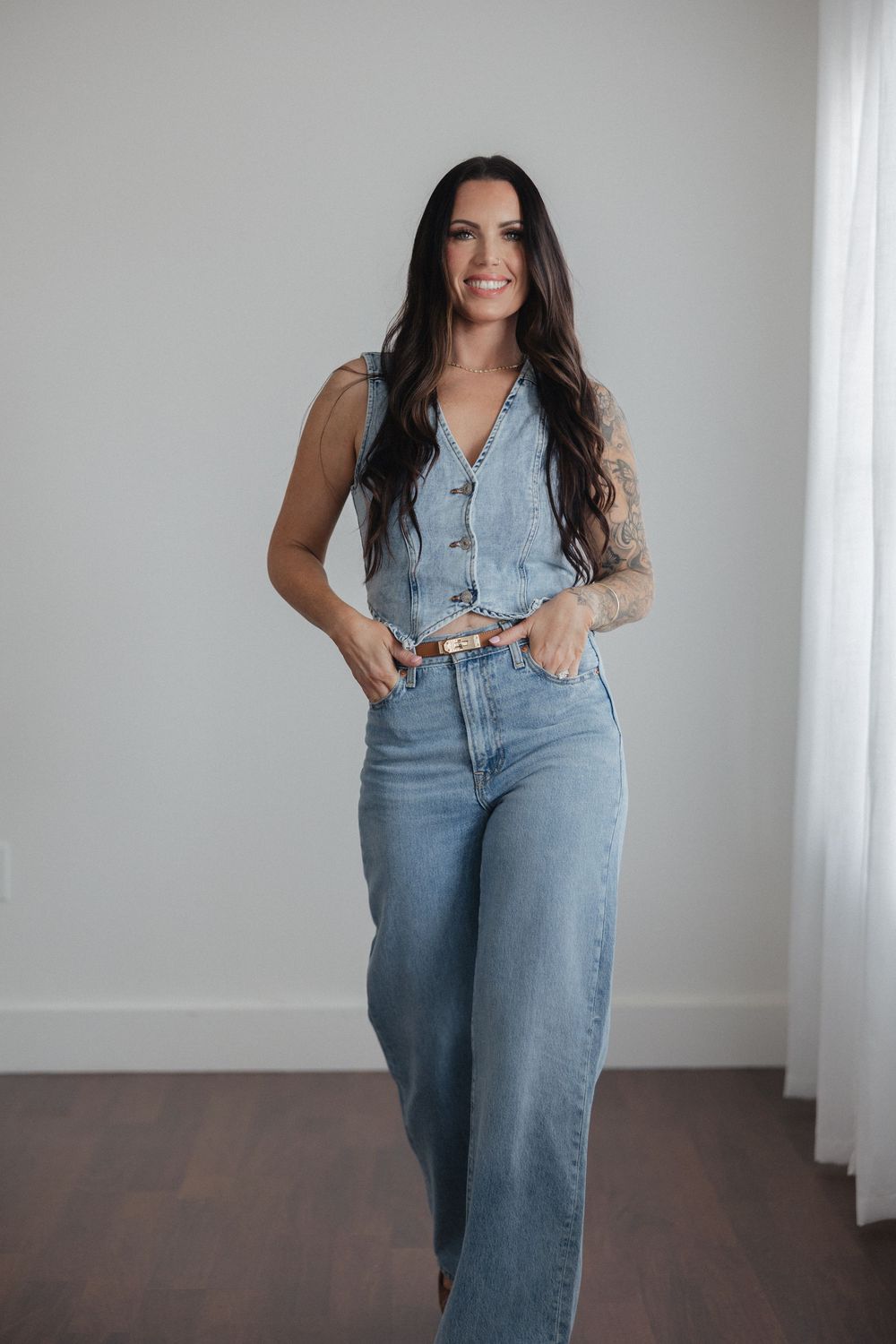 Person in light denim vest and jeans poses against white wall in multiple casual fashion shots.