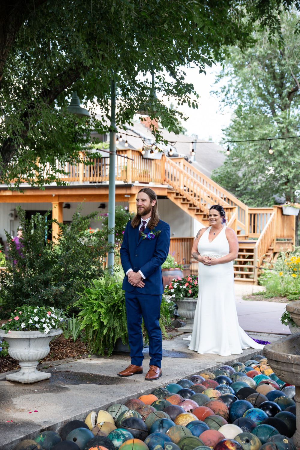 A first look wedding moment in a garden setting with wooden staircase and colorful glass art.