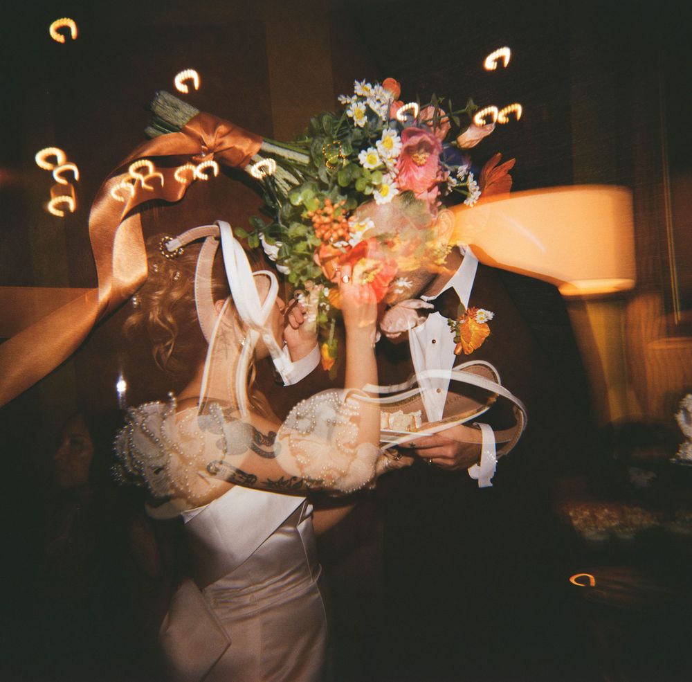 A bride holds a colorful wedding bouquet with motion blur effects creating a dreamy, swirling atmosphere at a reception.