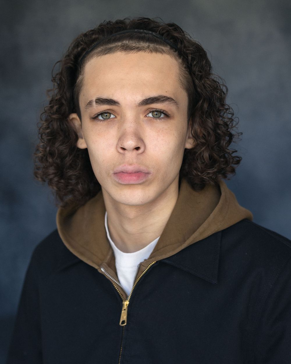Teenage boy actor headshot with curly hair wearing brown hoodie for character portrait photography