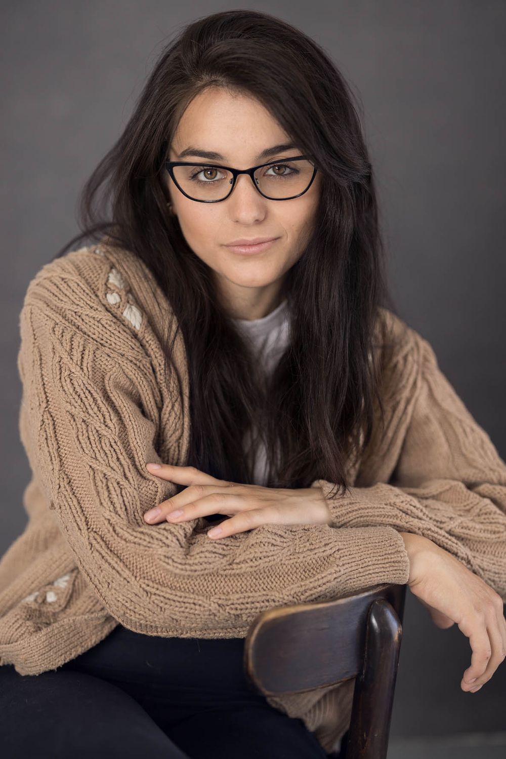 Young woman actor headshot wearing glasses and tan cable knit sweater for intellectual character portfolio