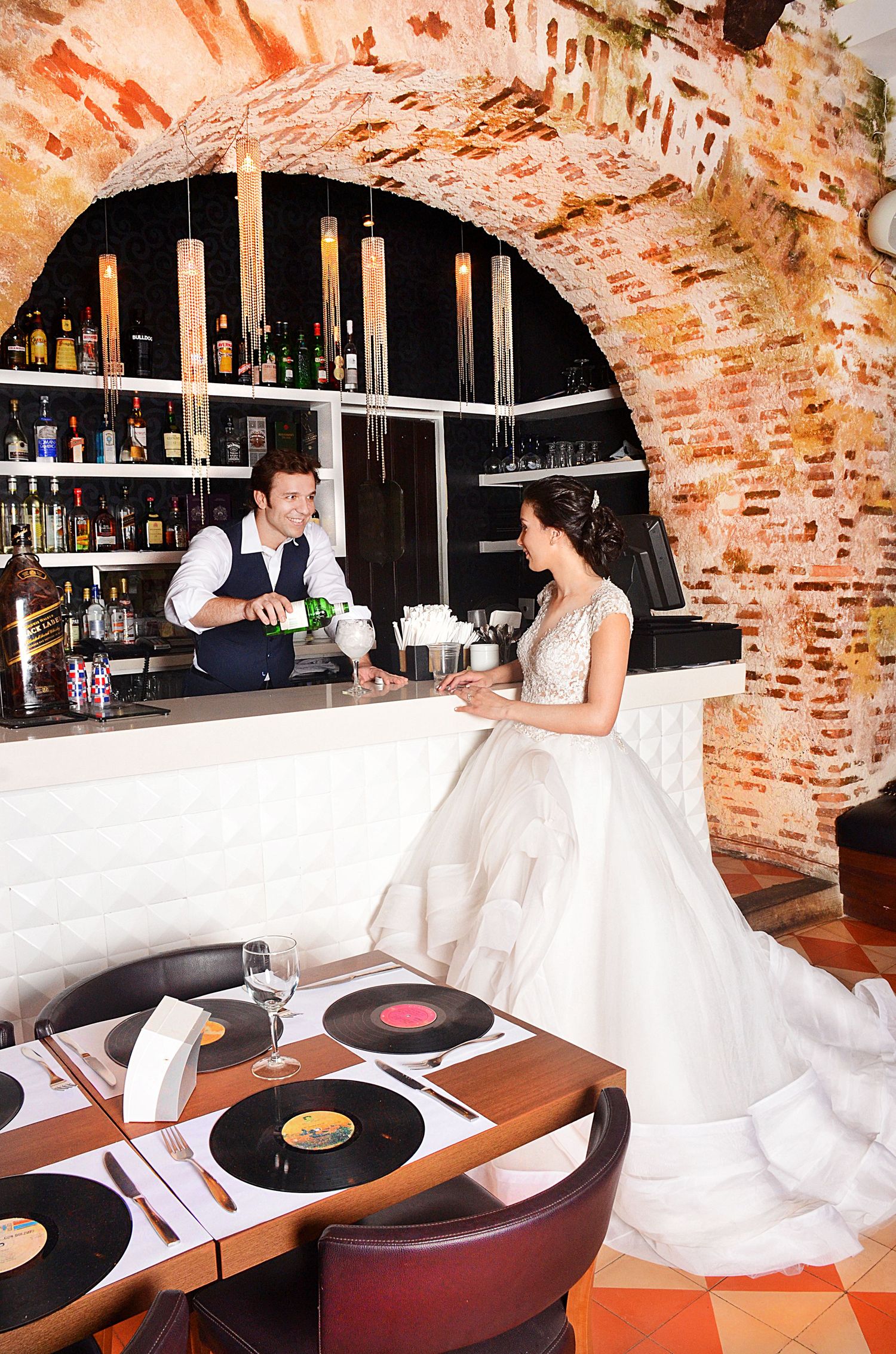 Vintage bar interior with exposed brick archway features vinyl records and a marble-top counter.