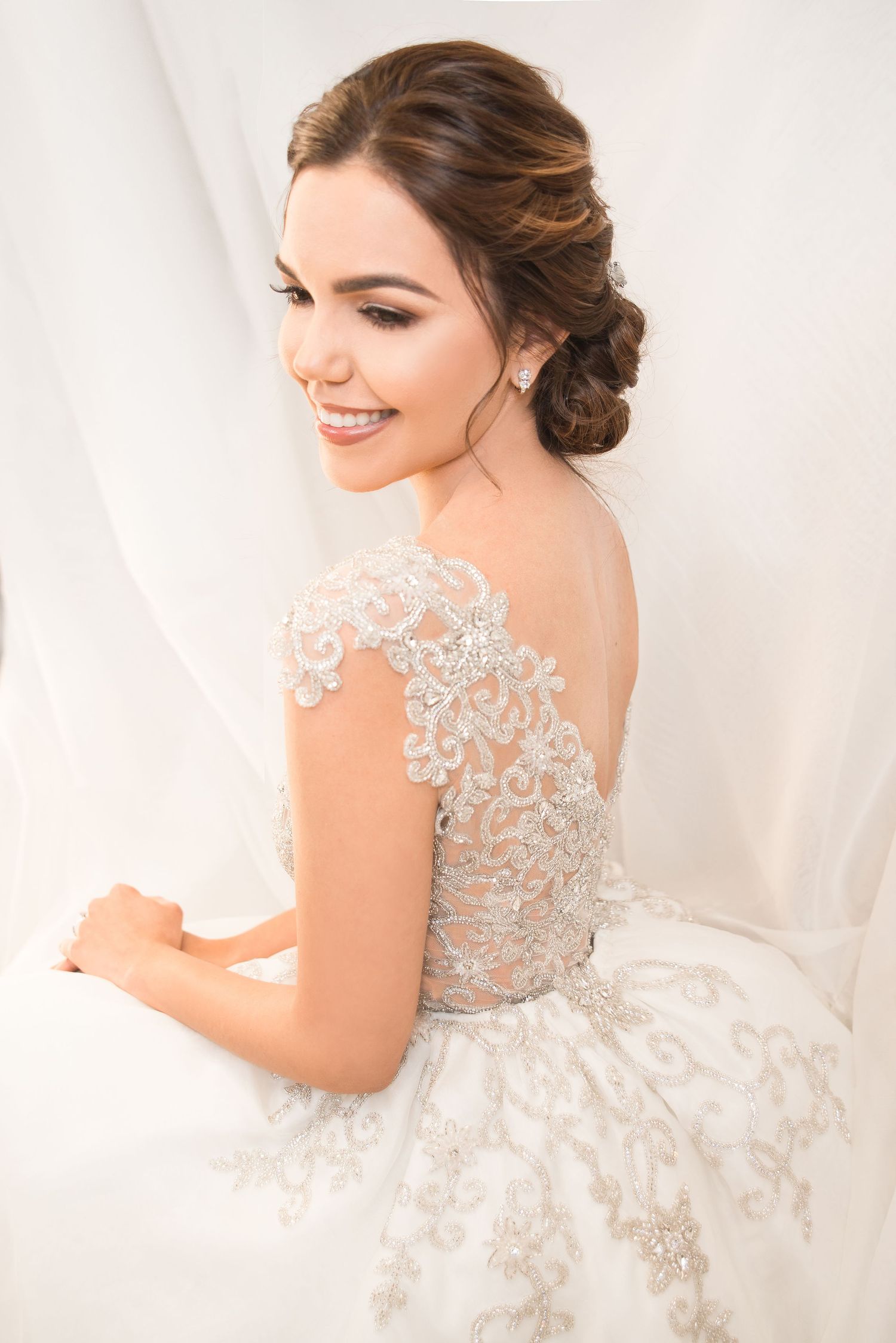 An elegant bridal portrait showcasing delicate lace details and romantic upswept hairstyling.