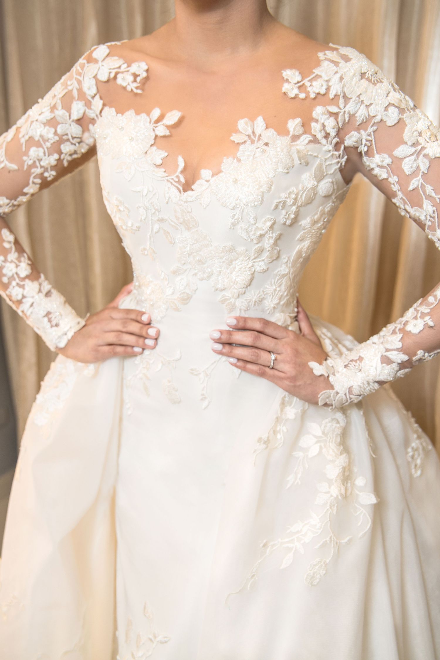Elegant wedding dress features delicate floral lace long sleeves and illusion neckline with intricate applique details.