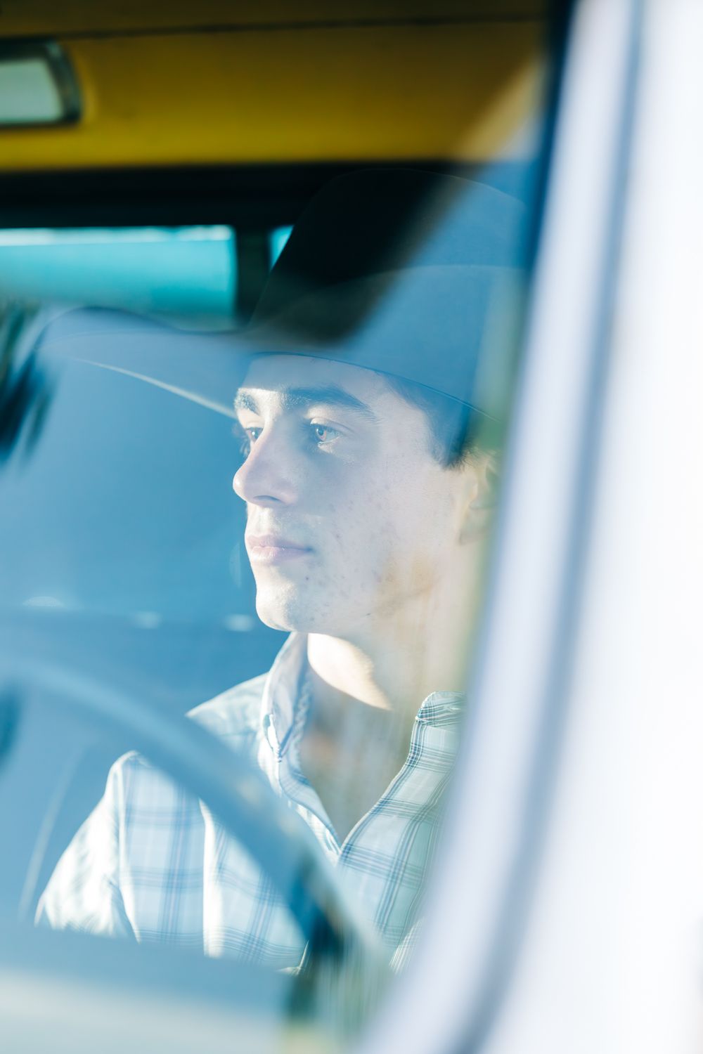 Senior boy in a cowboy hat sitting in his truck looking away, Casmalia, CA.